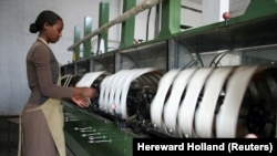 FILE: A woman spins raw silk yarn in a factory owned by Rwandan textile firm Utexwra in the capital Kigali. Taken Jan. 19, 2009.