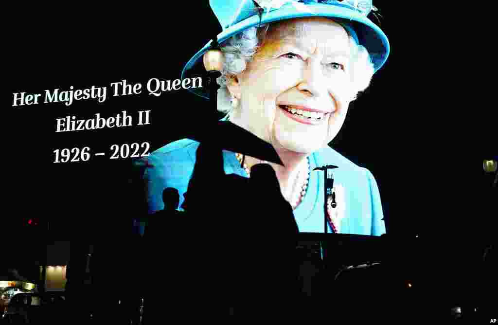 People pass by an image of Queen Elizabeth II projected onto a large screen at Piccadilly Circus, in London, Sept. 8, 2022. 