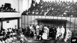 The Duchess of Kent, seated center on dais, reads a message from the Queen of England in the Parliament House at Accra, Ghana, on March 6, 1957.