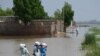 Sejumlah warga berjalan melintasi area yang tergenang banjir di pinggiran kota Jacobabad, Pakistan, pada 6 September 2022. Mereka berjalan pulang kembali ke rumah dengan membawa bantuan makanan. (Foto: AFP/Aamir Qureshi)