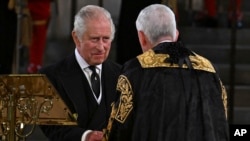 Speaker of the House of Commons Sir Lindsay Hoyle, right, gestures to King Charles III at Westminster Hall, where both Houses of Parliament met to express their condolences following the death of Queen Elizabeth II, in London, Sept. 12, 2022. 