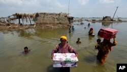 Warga membawa barang-barang yang masih bisa diselamatkan di distrik Qambar Shahdadkot, provinsi Sindh, yang dilanda banjir parah di Pakistan, Selasa (6/9). 