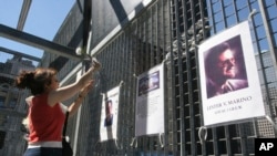 FILE - Kathy Haberman places a flower and card in memory of her daughter Andrea Haberman on a gate with other memorial images surrounding ground zero, the site where the World Trade Center once stood in New York, Sept. 10, 2005.