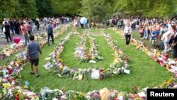 People honor the late Queen Elizabeth II by leaving gifts and flowers in Green Park near Buckingham Palace in London, Sept. 11, 2022.