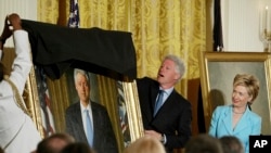 FILE - Former President Clinton, center, unveils his portrait as he and former first lady Hillary Clinton, right, participate in a ceremony for the unveiling of the their portraits, June 14, 2004, at the White House.