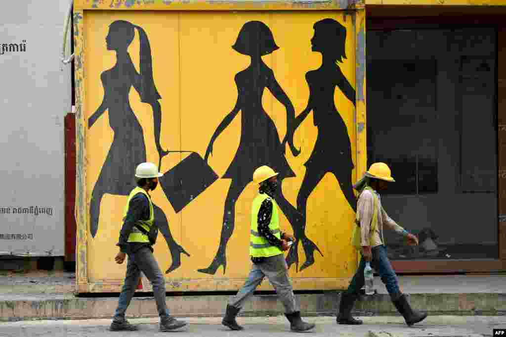 Construction workers walk past a mural in Phnom Penh, Cambodia, Sept. 6, 2022. (Photo by TANG CHHIN Sothy / AFP)