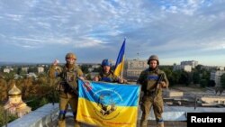 Украинские военные развернули флаг страны на крыше здания в Купянске, 10 сентября 2022 года