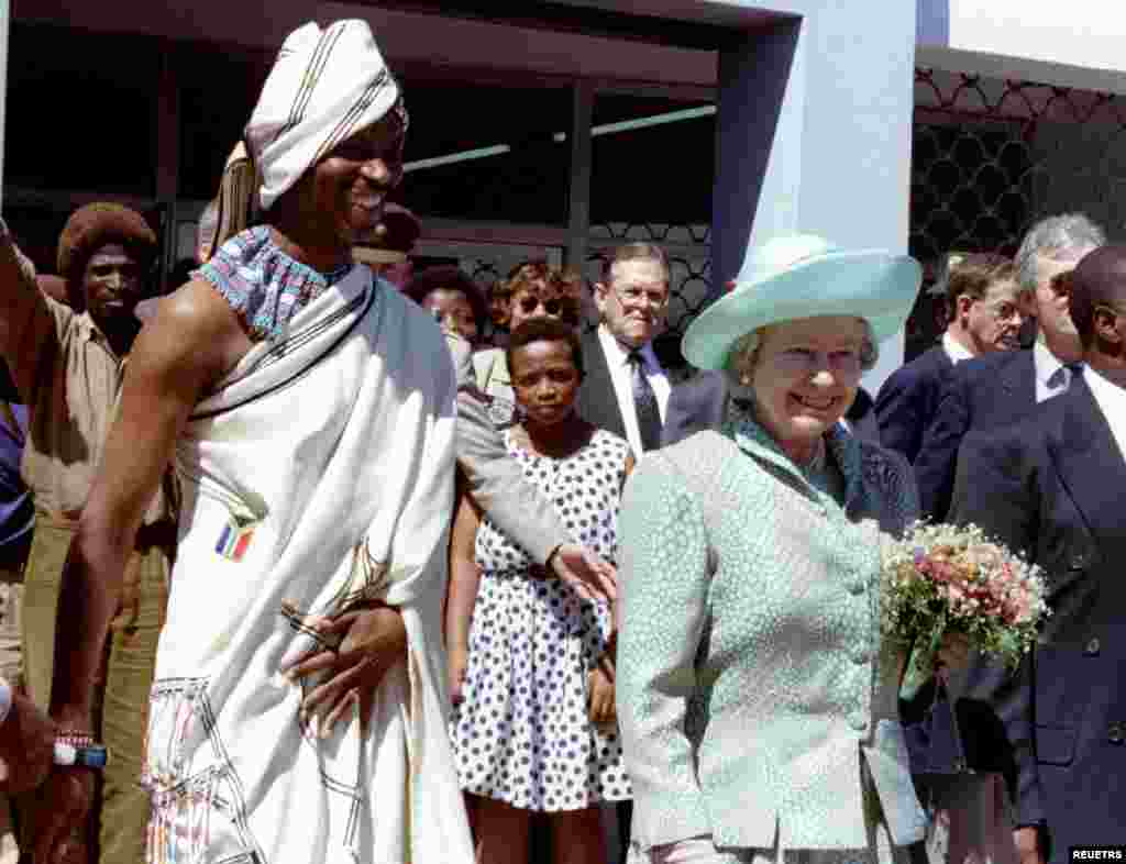 Britain&#39;s Queen Elizabeth II, accompanied by Port Elizabeth mayor Nceba Faku, in Xhosa traditional dress, smile at residents outside the Centenary hall in New Brighton township, March 22, 1995. The Queen is on a six-day official visit to South Africa, her first to the country since 1947.