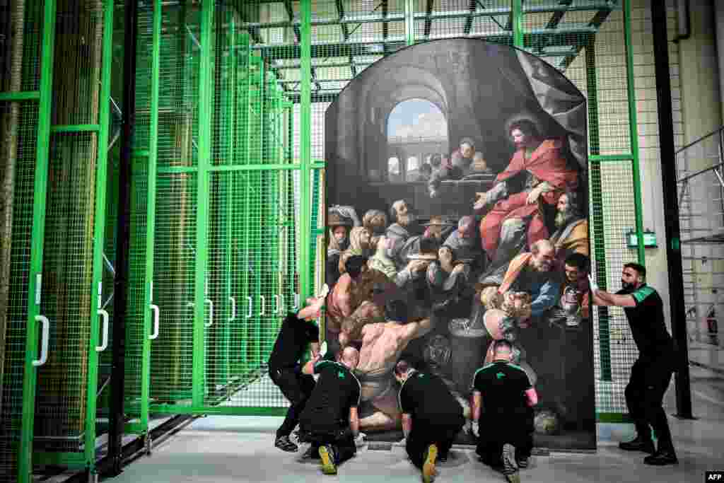 Workers carry a painting at the paintings&#39; restoration site for the Notre Dame Cathedral on the outskirts of Paris, France, Sept. 6, 2022. (Photo by STEPHANE DE SAKUTIN / AFP)
