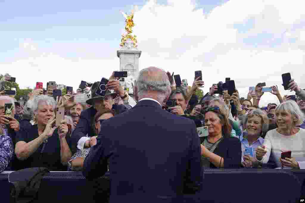 Britain&#39;s King Charles III, with his back to the camera, greets well-wishers as he walks by the gates of Buckingham Palace following Thursday&#39;s death of Queen Elizabeth II, in London.