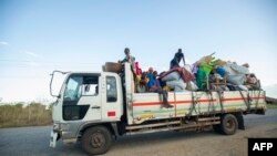 FILE - Displaced families from the community of Impire in the Cabo Delgado province, travel on a flatbed truck as they flee on June 14, 2022 armed insurgents who attacked their community two days earlier. 