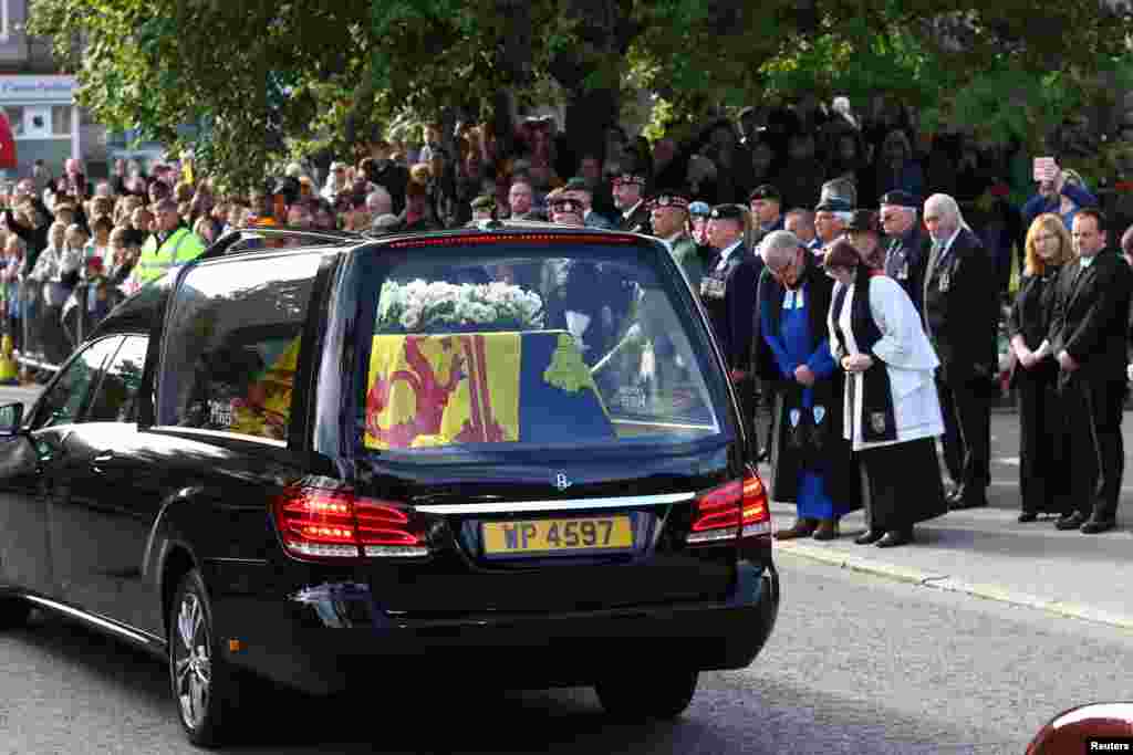 People pay respects to Queen Elizabeth as the hearse carrying her coffin&nbsp; passes through the village of Ballater, near Balmoral, Scotland, Sept. 11, 2022.