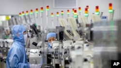 FILE - Employees wearing protective equipment work at a semiconductor production facility for Renesas Electronics during a government organized tour for journalists in Beijing, on May 14, 2020. 