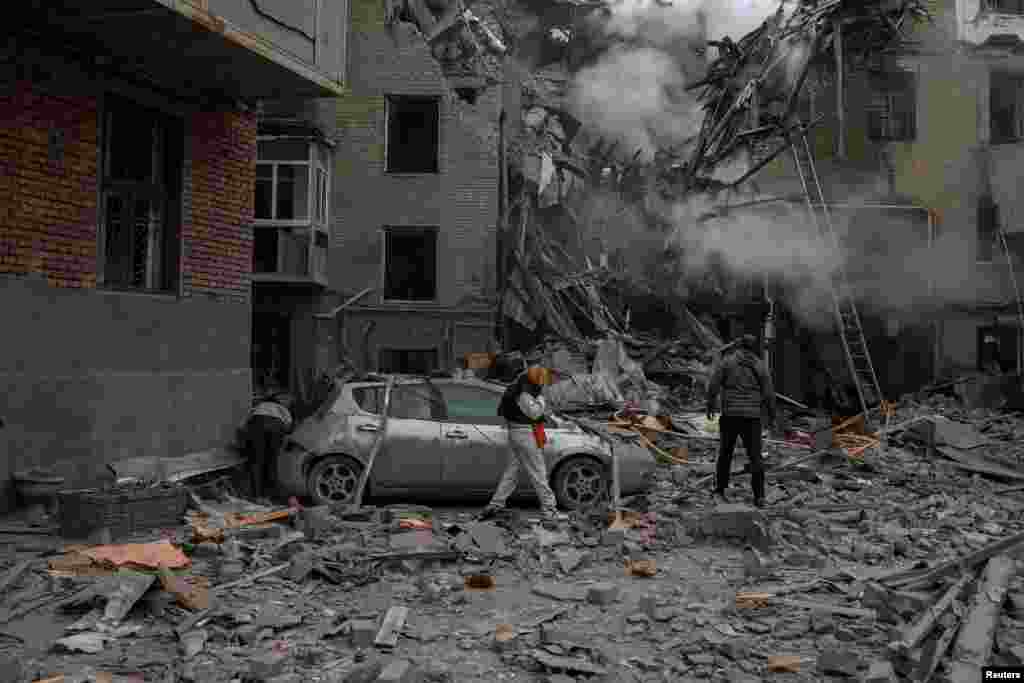 Local people look at debris of a building damaged by a Russian military strike, in Kharkiv, Ukraine.