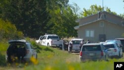 In this image taken from video, Canadian law enforcement personnel surround a residence on the James Smith Cree First Nation reserve in Saskatchewan, Canada, Sept. 6, 2022, as they search for a suspect in a series of stabbings. 