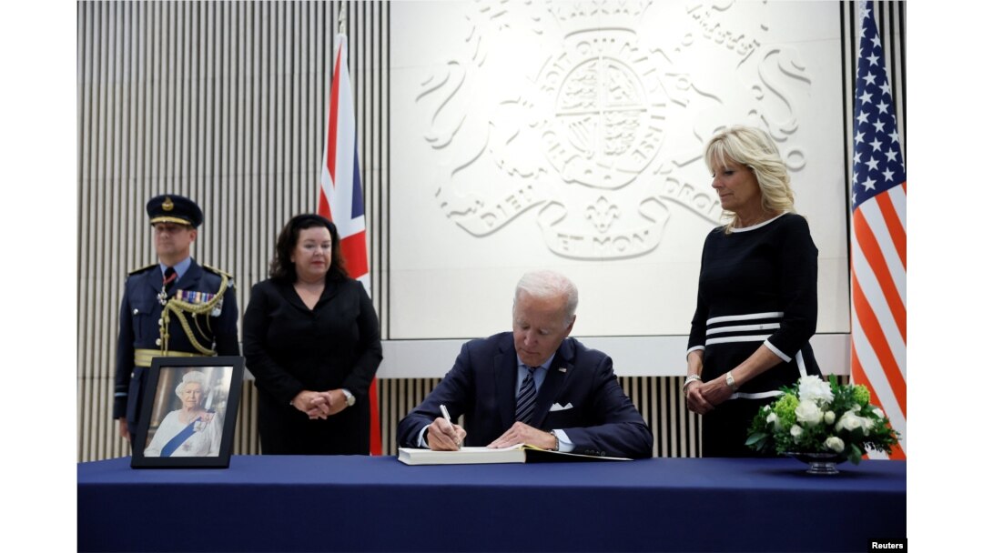 Presiden AS Joe Biden menandatangani buku belasungkawa saat ibu negara AS Jill Biden memandang foto Ratu Elizabeth, raja terlama yang memerintah Inggris dan tokoh negara selama tujuh dekade, meninggal pada usia 96, di Kedutaan Besar Inggris, di Washington, AS, 8 September, 2022. (REUTERS/Evelyn Hockstein)