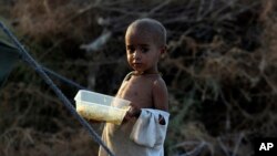 A child displaced by flooding from monsoon rains eats food at a make-shift tent camp for flood victims, in Sukkur, Pakistan, Sept. 7, 2022.