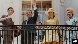 Presiden Richard Nixon melambaikan tangannya dari balkon Executive Mansion di saat ia dan ibu negara Pat Nixon (kanan) bertemu dengan Pangeran Charles (kiri) dan Putri Anne dari Inggris, pada 16 Juli 1970. (Foto: AP)