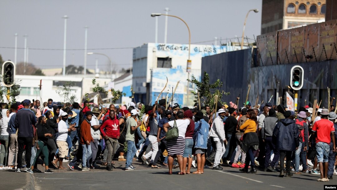Para pengunjuk rasa yang membawa tongkat berpawai melewati jalan-jalan menyusul penahanan mantan presiden Afrika Selatan, Jacob Zuma, di tengah kekerasan yang merembet ke Johannesburg, Afrika Selatan, Minggu, 11 Juli 2021. 