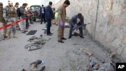 Security personnel check weapons as the bodies of militant fighters, wearing military uniforms, lie inside the Interior Ministry after a deadly attack, in Kabul, Afghanistan, May 30, 2018.