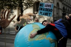 An Extinction Rebellion climate change protester hugs an inflatable planet Earth, near Downing Street in London, Britain, Oct. 8, 2019.