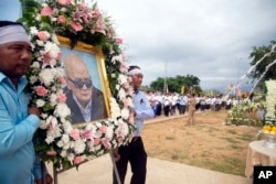 Relatives carry a portrait of former Khmer Rouge's chief ideologist and No. 2 leader, Nuon Chea, during his funeral procession in Pailin in northwestern Phnom Penh, Cambodia, Aug. 9, 2019.