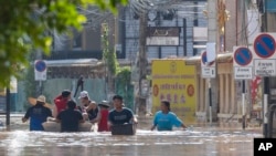 People wade through floodwaters in Chiang Mai Province, Thailand, Oct. 6, 2024 as the city's main river overflowed its banks following heavy seasonal rainfall. 