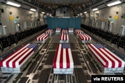 FILE - Flag-draped transfer cases of U.S. military service members who were killed by an August 26 suicide bombing at Kabul's Hamid Karzai International Airport line the inside of a C-17 Globemaster II prior to transfer at Dover Air Force Base, Delaware, Aug. 29, 2021. (U.S. Marines/Handout via Reuters)