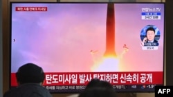People watch a television screen showing a news broadcast with file footage of a North Korean missile test, at a railway station in Seoul, South Korea, on Jan. 30, 2022.