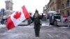 A protester stands in front of parked vehicles in downtown Ottawa, Ontario, February 3, 2022.