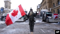 A protester stands in front of parked vehicles in downtown Ottawa, Ontario, February 3, 2022.