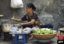 FILE - A roadside food vendor sells snail noodles in Hanoi, Oct. 10, 2003.