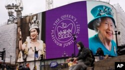A man feeds birds as the screen in Piccadilly Circus is lit to celebrate the 70th anniversary of Britain&#39;s Queen Elizabeth&#39;s accession to the throne, in London.