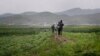 FILE - A man and woman carry their bicycle through farm fields in Pyongsong, North Korea. 