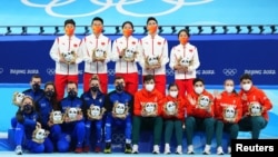 Các vận động viên Trung Quốc (đứng) ngày thứ Bảy đoạt huy chương vàng đồng đội tiếp sức hỗn hợp cho môn trượt băng tốc độ cự ly ngắn tại Thế vận hội Mùa đông Bắc Kinh. Ý (trái) đoạt huy chương bạc và Hungary huy chương đồng.