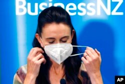 New Zealand Prime Minister Jacinda Ardern removes her mask before she outlines the Government's plans, Feb. 3, 2022, that will dismantle its quarantine system and reopen its borders the world.