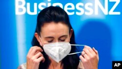 New Zealand Prime Minister Jacinda Ardern removes her mask before she outlines the Government's plans, Feb. 3, 2022, that will dismantle its quarantine system and reopen its borders the world.