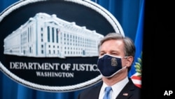 FBI Director Christopher Wray listens during a virtual news conference at the Department of Justice, October 28, 2020, in Washington. The Justice Department has charged eight people with working on behalf of the Chinese government.