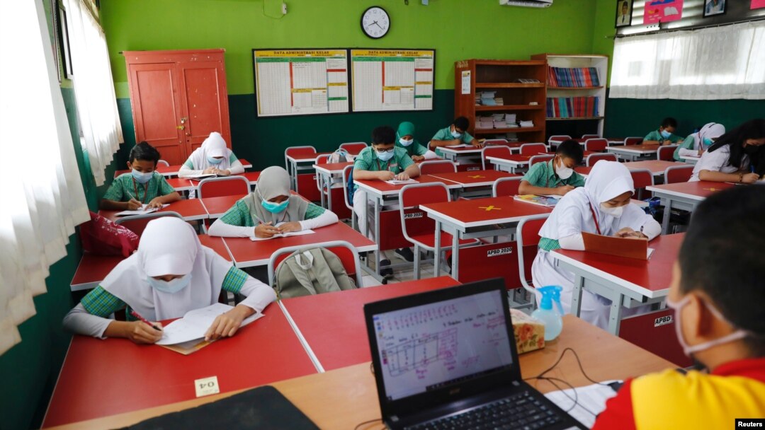 Siswa sekolah dasar mengenakan masker dan duduk sesuai aturan untuk menjaga jarak sosial, kembali belajar di kelas mereka, saat sekolah dibuka kembali di tengah pandemi COVID-19 di Bekasi, 24 Maret 2021. (REUTERS / Willy Kurniawan)
