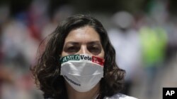 A woman wears a face mask with text reading in Spanish "AMLO, leave already," during a protest demanding the resignation of Mexican President Andres Manuel Lopez Obrador, Aug. 30, 2020.