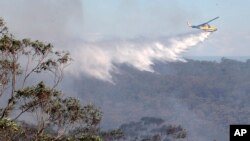 A helicopter drops water on bush land in Faulcombridge, 85 kilometers (53 miles) west of Sydney, Australia, Oct. 24, 2013.