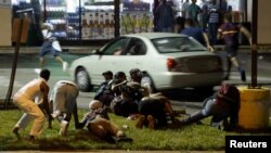 Manifestantes se cubren de los disparos en Ferguson, Missouri, durante los eventos de la noche del domingo.