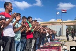 FILE - Egyptian volunteers pray the absent prayers for victims of the Israeli airstrikes on Gaza, at the Rafah crossing port, Egypt, Wednesday, Oct. 18, 2023.