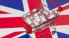 FILE PHOTO: A small shopping basket filled with vials labeled "COVID-19 - Coronavirus Vaccine" is placed on a UK flag