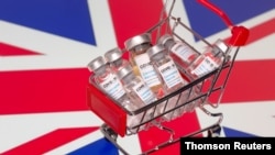 FILE PHOTO: A small shopping basket filled with vials labeled "COVID-19 - Coronavirus Vaccine" is placed on a UK flag