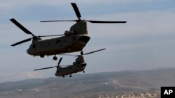 ເຮລີຄັອບເຕີ ສະຫະລັດ U.S. CH-47 Chinooks ບິນຜ່ານເຂດຊ້ອມຮົບຈຳລອງໃນລະຫວ່າງການຝຶກຊ້ອມທະຫານ NATO ໃນເມືອງ Zaragoza, ສເປນ, 4 ພະຈິກ, 2015. 
