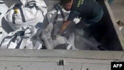 Seorang polisi Spanyol menemukan seorang migran yang bersembunyi di dalam karung limbah beracun di pelabuhan di pelabuhan Melilla, Spanyol, di sebelah utara pantai Maroko, 19 Februari 2021. (Foto: Handout/Spanish Guardia Civil/AFP)