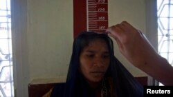 A 26-year-old woman stands against markings on a wall as a nurse measures her height at a community health center in India. (file)