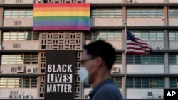 Un hombre camina frente a una pancarta de Black Lives Matter y de una bandera de arcoíris en la embajada de Estados Unidos en Corea del Sur, el domingo 14 de junio de 2020. 