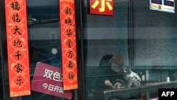 A woman with her dog plays a scratch-off lottery ticket in a lottery store at a shopping mall in Beijing, Feb. 6, 2025.